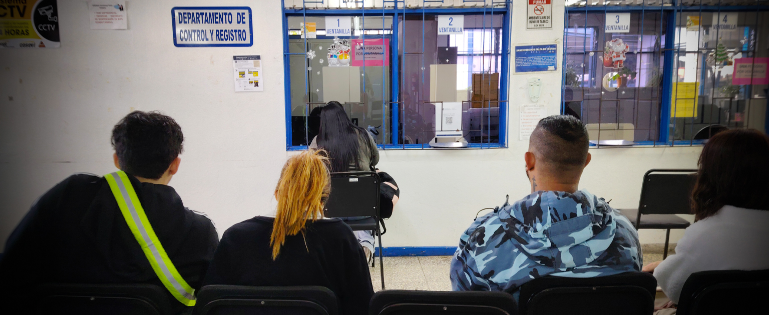 Personas de espaldas sentadas en hilera esperando ser atendidas para habilitar sus credenciales de ingreso al sistema de licencias