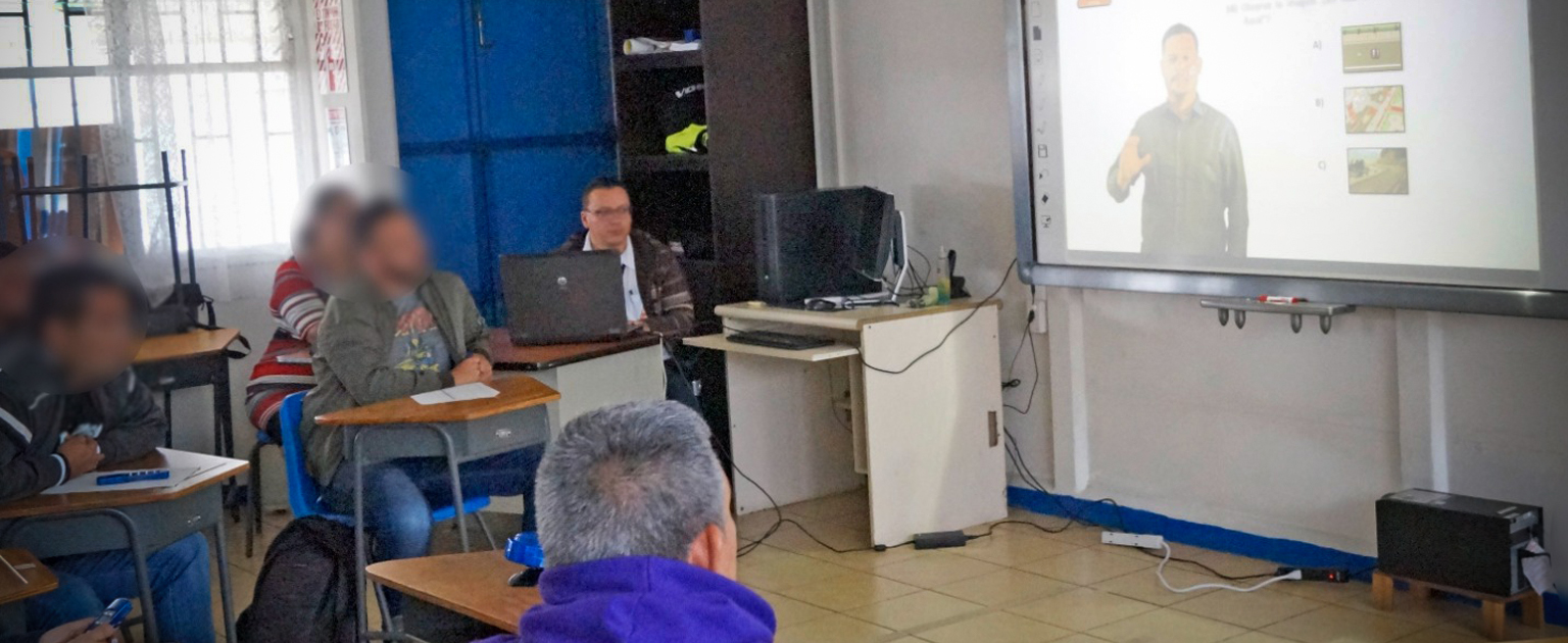 Personas participan en el curso teórico de manejo para población sorda, utilizando material visual e interpretación en lengua de señas.