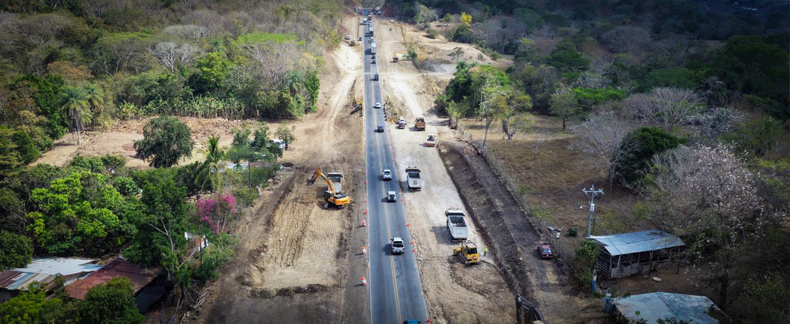 Vista aérea de las obras de ampliación e intervención del tramo Barranca–Limonal. Se observa la carretera en operación con tránsito vehicular mientras se desarrollan trabajos de movimiento de tierras y construcción de nuevos carriles a ambos lados de la vía. En la zona se distinguen excavadoras, camiones, maquinaria pesada, áreas despejadas para la ampliación y sectores de vegetación propios del paisaje rural circundante.