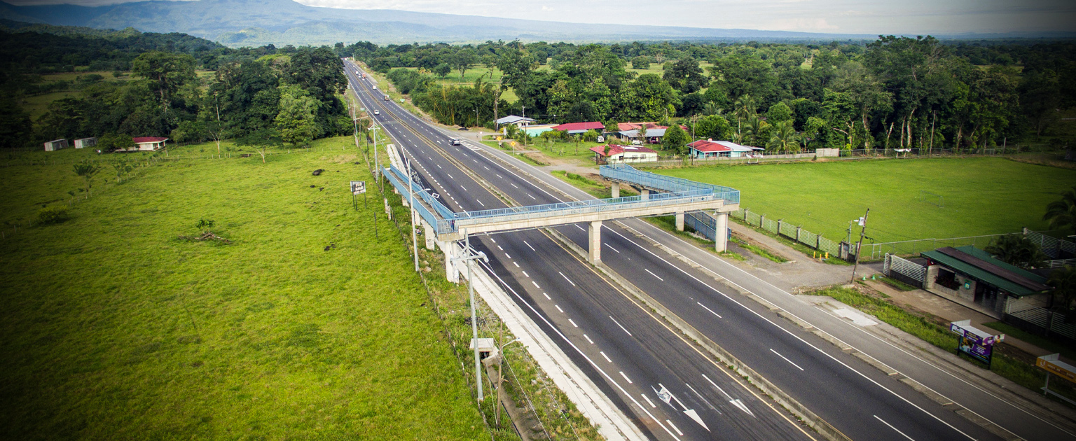 Fotografía aérea que muestra parte de la ruta 32 a cuatro carriles y un puente peatonal