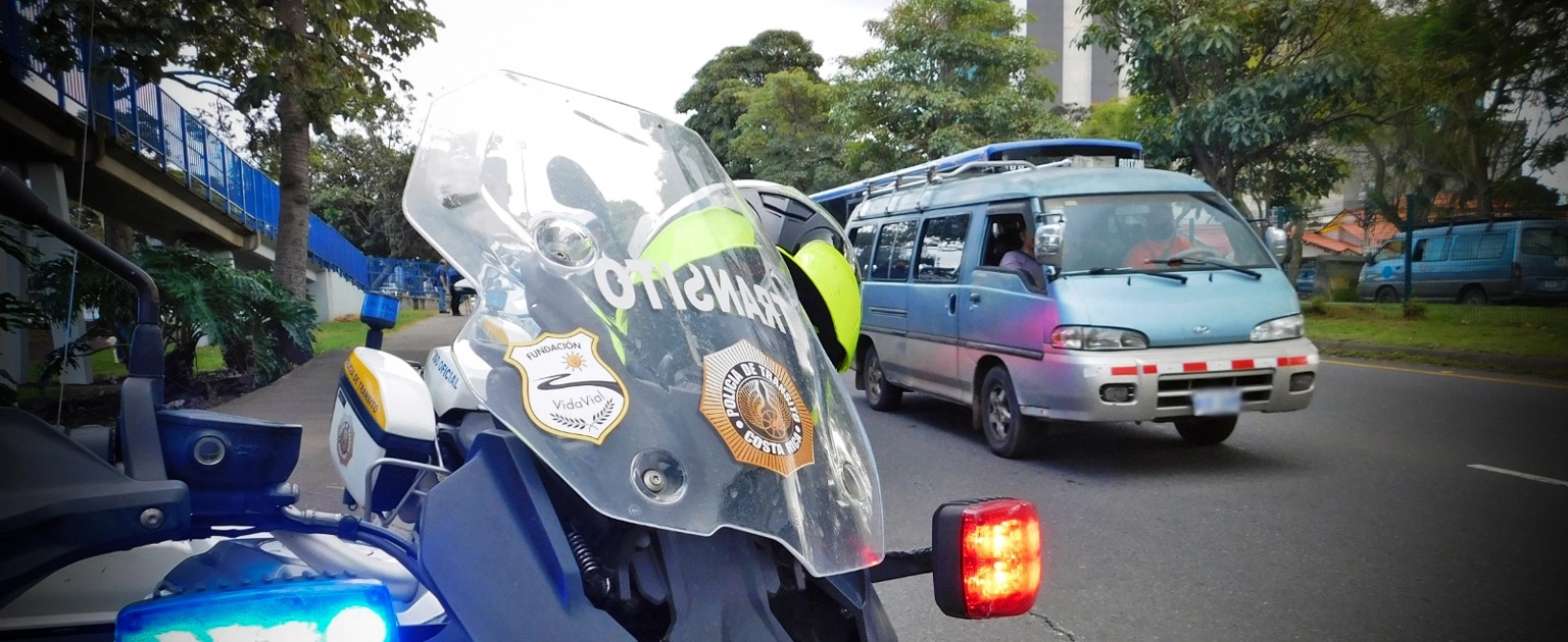 Fotografía que muestra un moto del tránsito y vehículos particulares en carretera