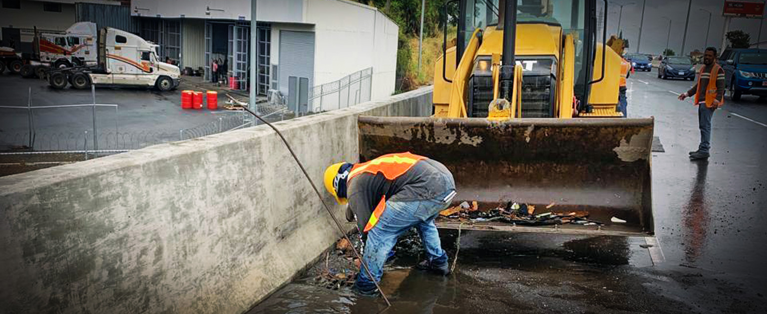 Fotografía que muestra a trabajadores con maquinaria recogiendo la basura que obstruyó el paso del agua..