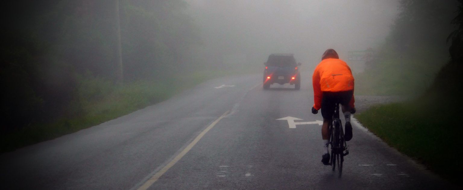 Ciclista con camisa llamativa en carretera con neblina