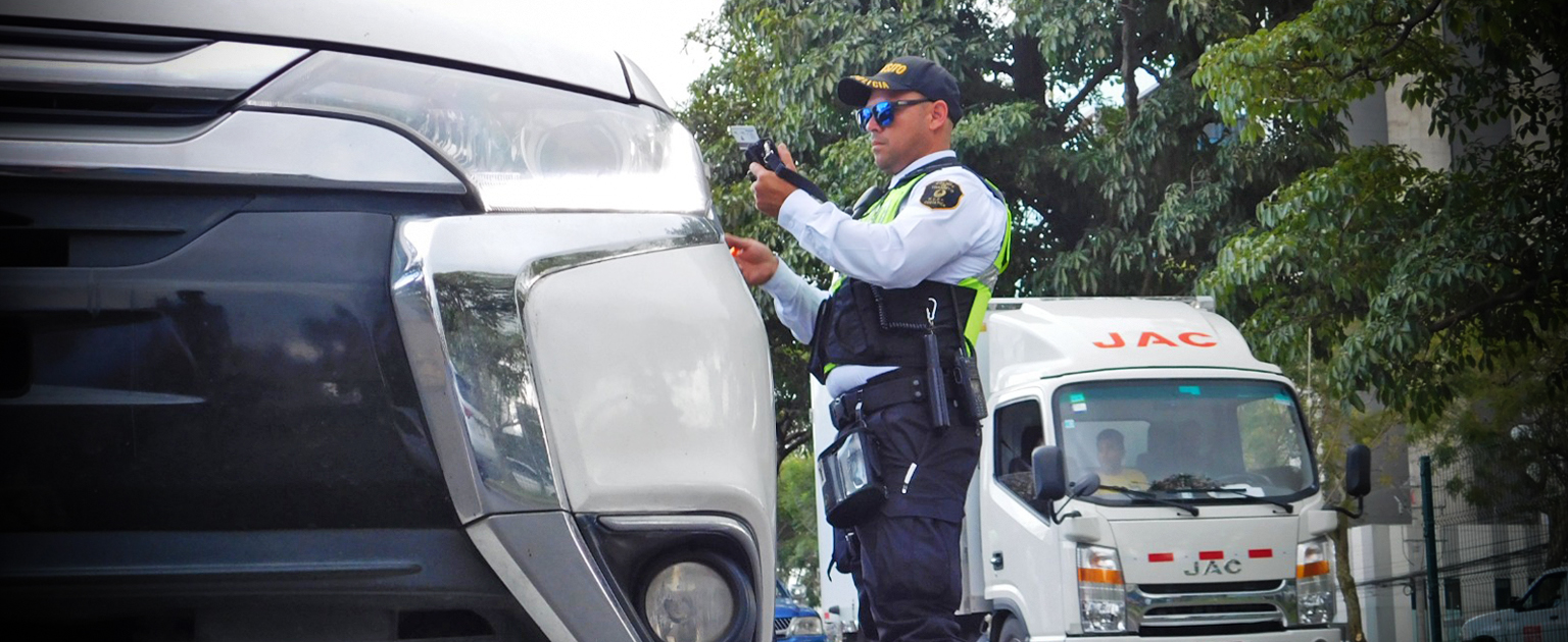 Oficial de tránsito generando una multa al lado de un vehículo  blanco