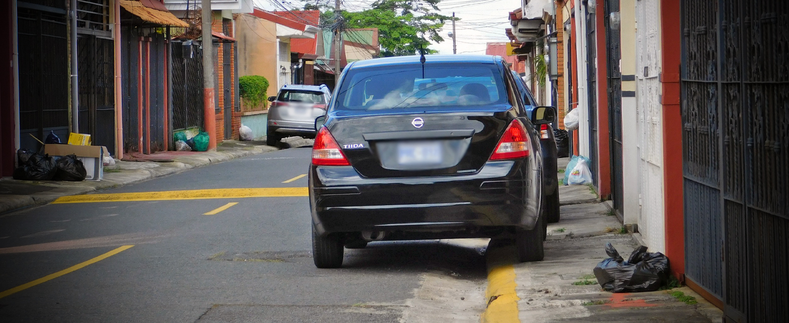 Fotografía que muestra un vehículo estacionado sobre raya amarilla