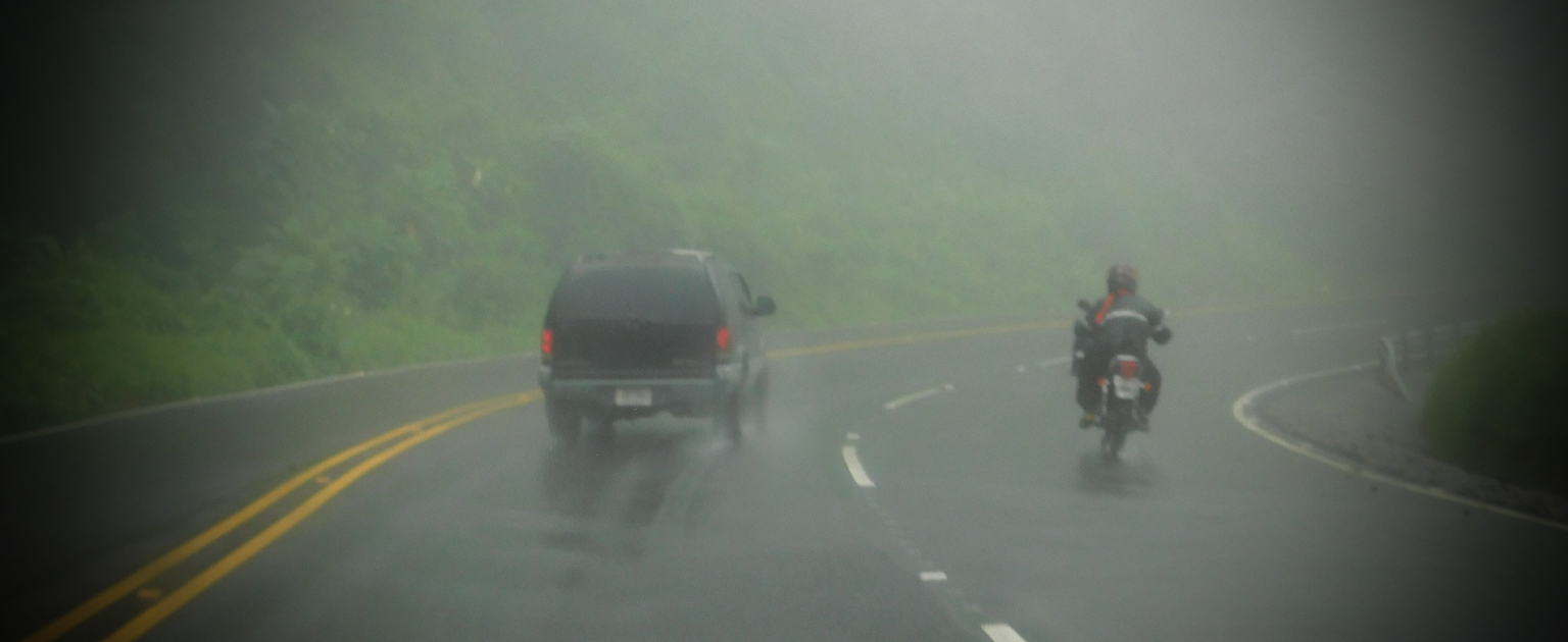 Fotografía que muestra vehículos circulando por una carretera en condiciones de lluvia