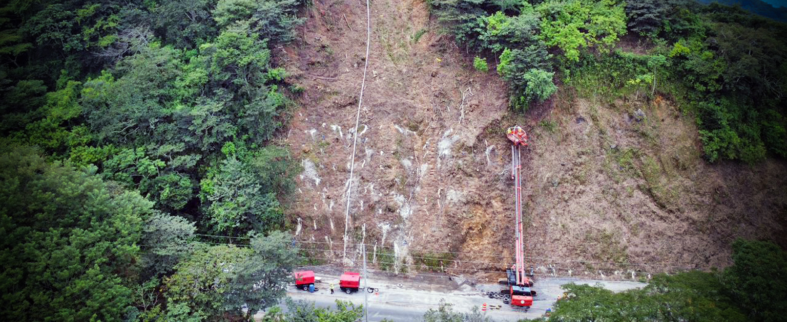 Maquinaria roja grande, trabajando en talud de montaña.