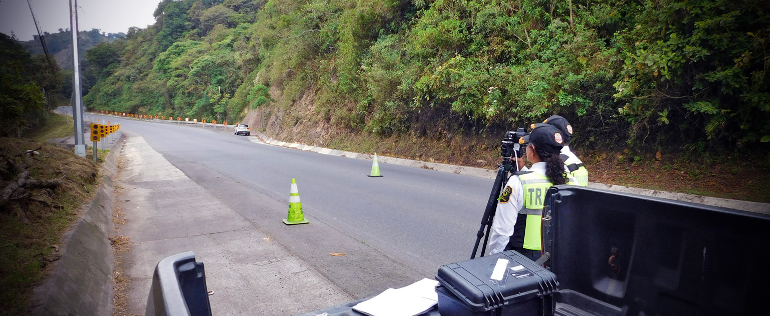 Dos oficiales de tránsito al lado de la carretera, utilizando un velocímetro. 