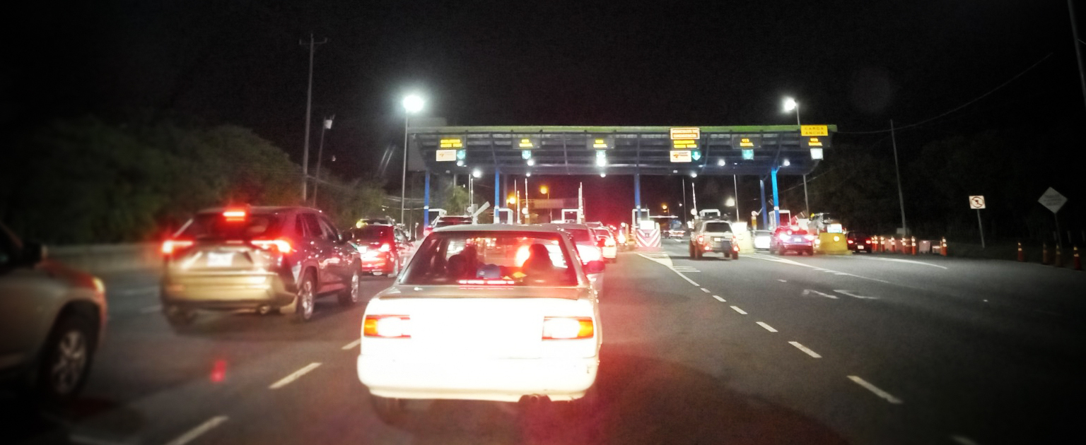 Vehículos haciendo fila en peaje. con luces encendidas