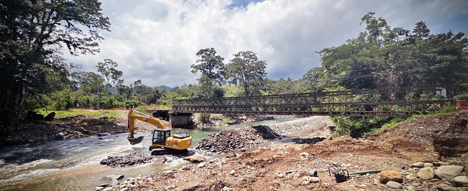 Maquinaria en río y al fondo estructura de puente