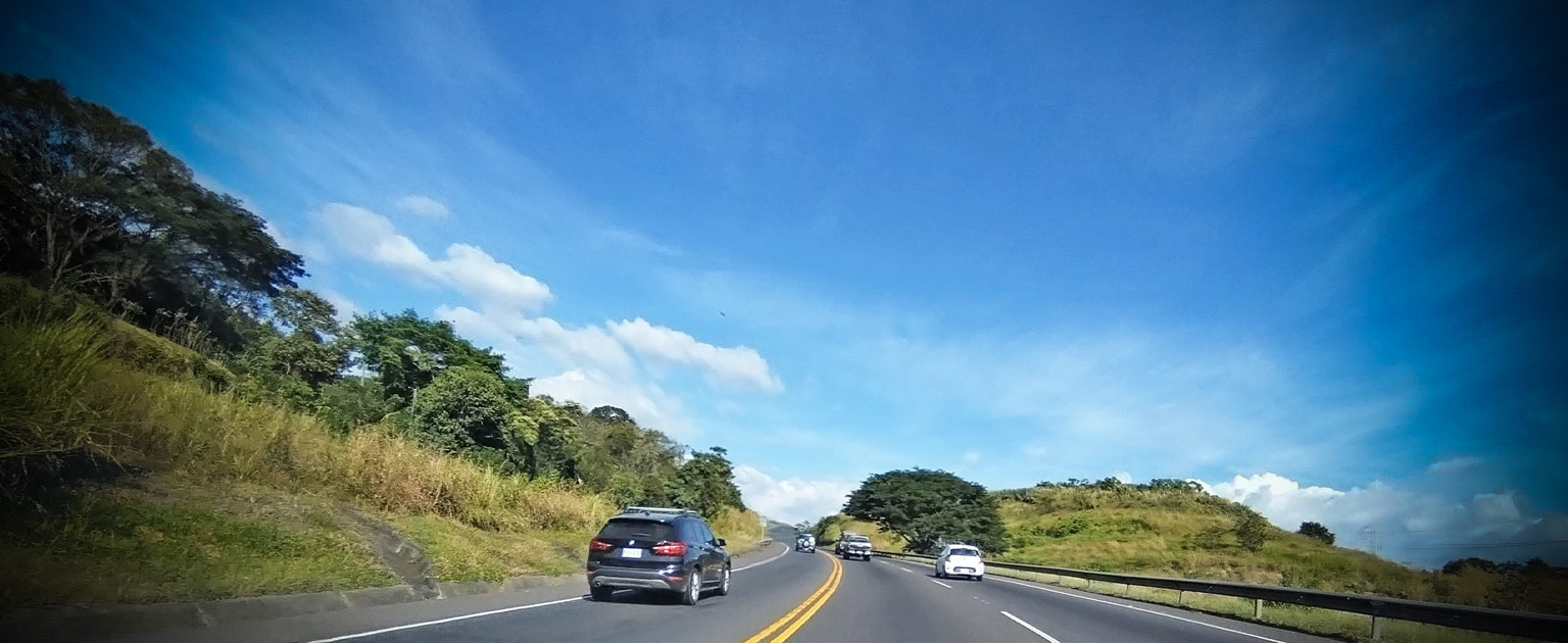 Carretera, con vehículo negro transitando. 