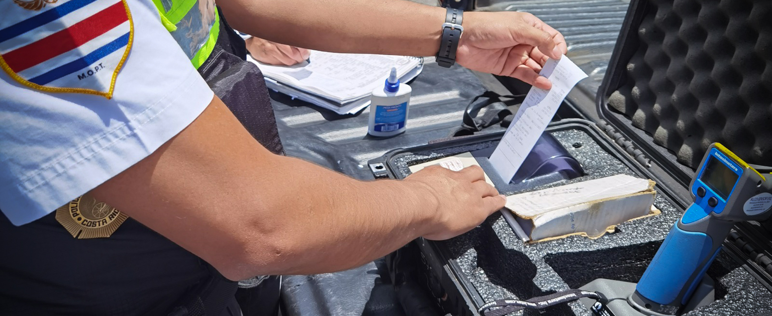 Imagen de manos de oficial de tránsito manipulando un alcoholímetro 