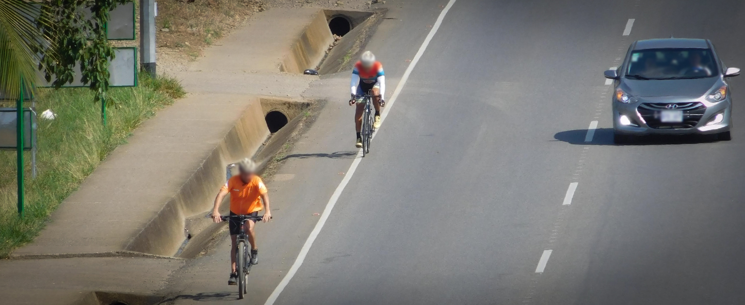 Fotografía que muestra un vehículo y dos ciclistas circulando
