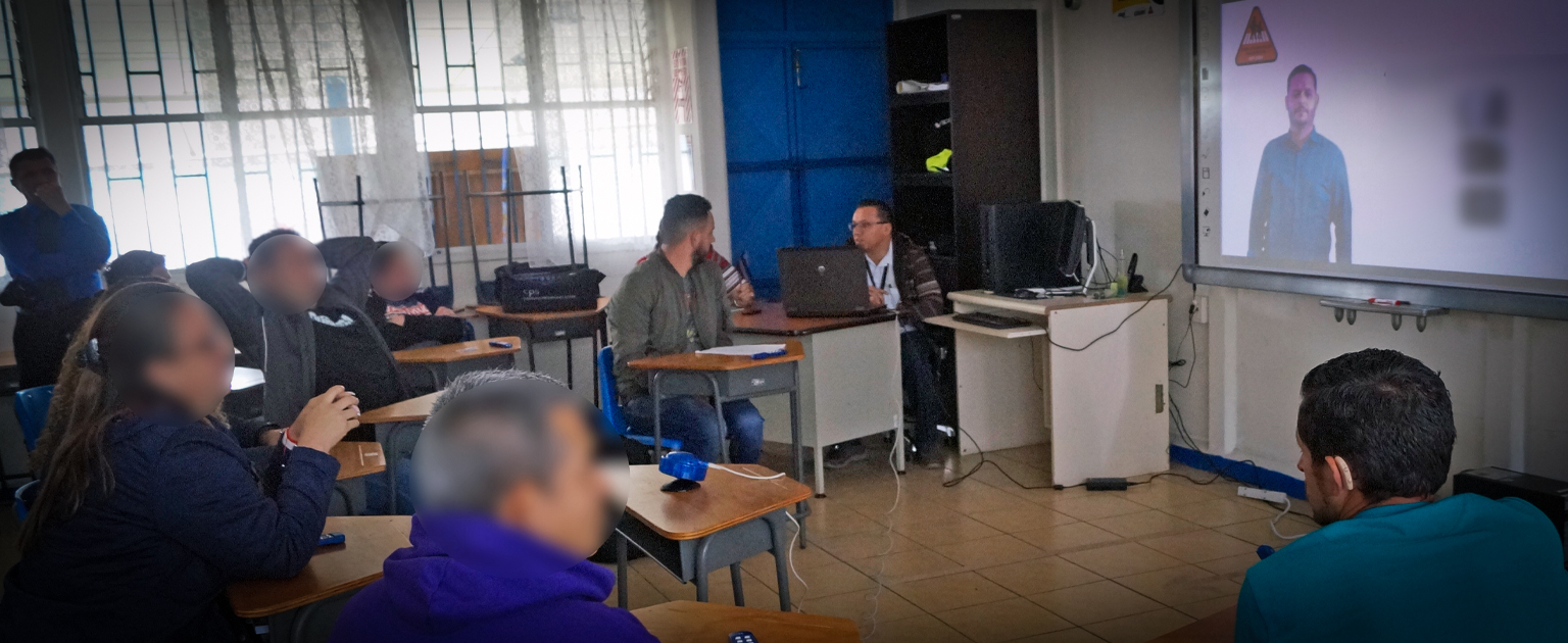 Fotografía que muestra a un grupo de personas en un aula aplicando el examen teórico para sordos