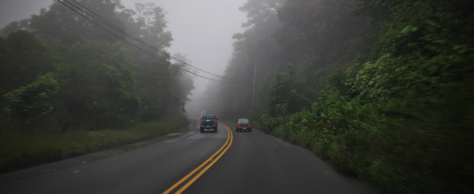 Fotografía que muestra una carretera con poca visibilidad por neblina y a un vehículo adelantando en zona de doble raya amarilla