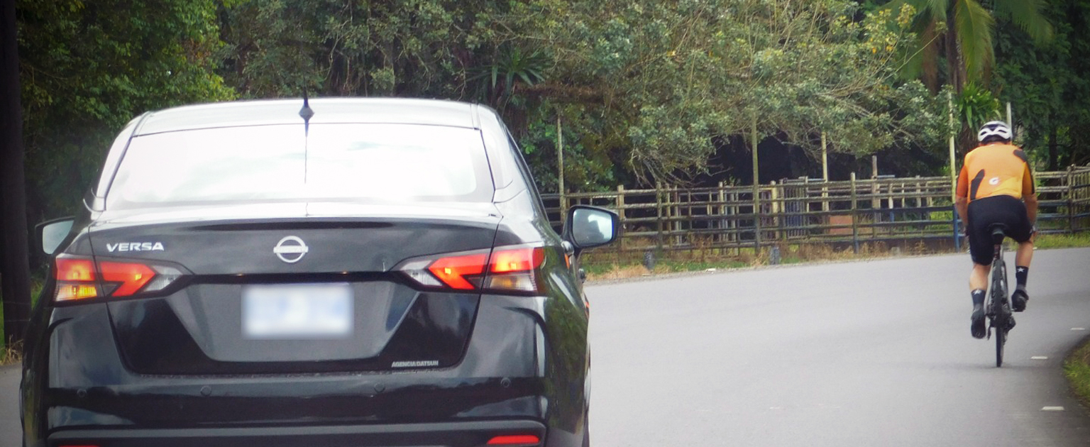Fotografía que muestra un vehículo del lado izquierdo de la vía y un ciclista del lado derecho