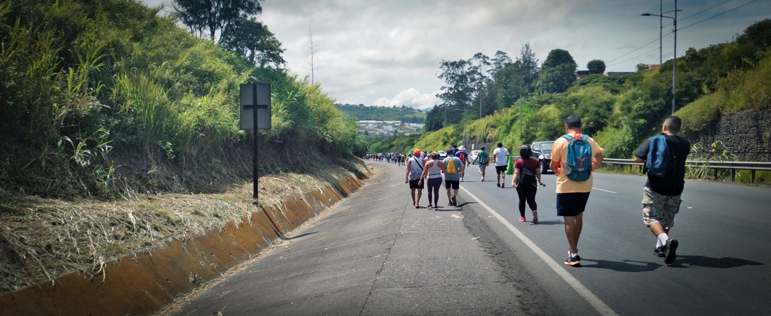 Grupo de romeros que camina por el espaldón de una carretera en el sector de Ochomogo. 