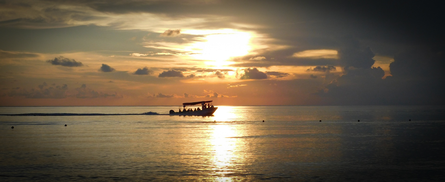 Fotografía que muestra una lancha sobre el mar en el atardecer