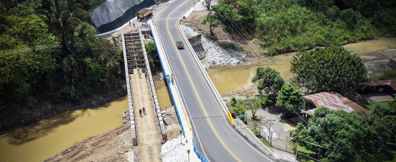 Vista aérea del nuevo puente sobre el río Pacuar, con circulación vehicular y al lado el  paso provisional que se está retirando.