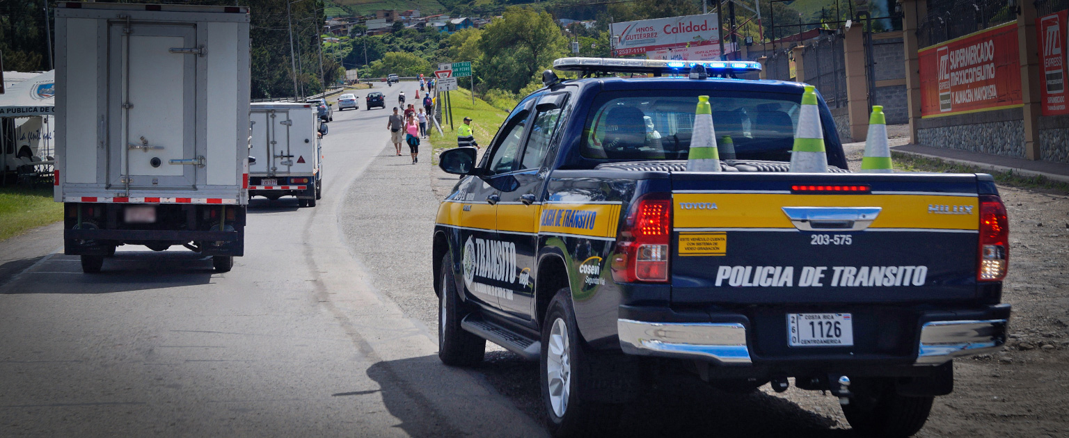 Patrulla de la Policía de Tránsito estacionada a la orilla de una carretera mientras supervisa la circulación vehicular y de romeros. 