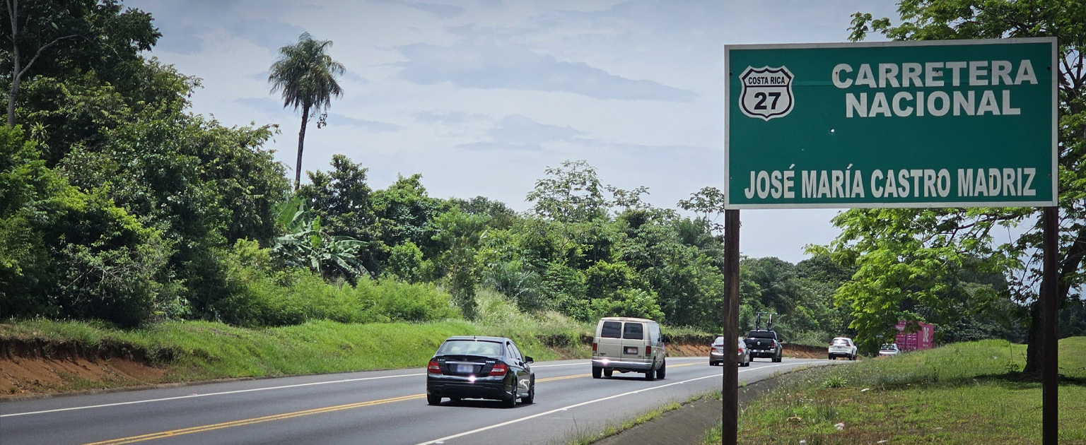Ruta Nacional 27 en Costa Rica, con vehículos en circulación y rótulo vial junto a zona boscosa