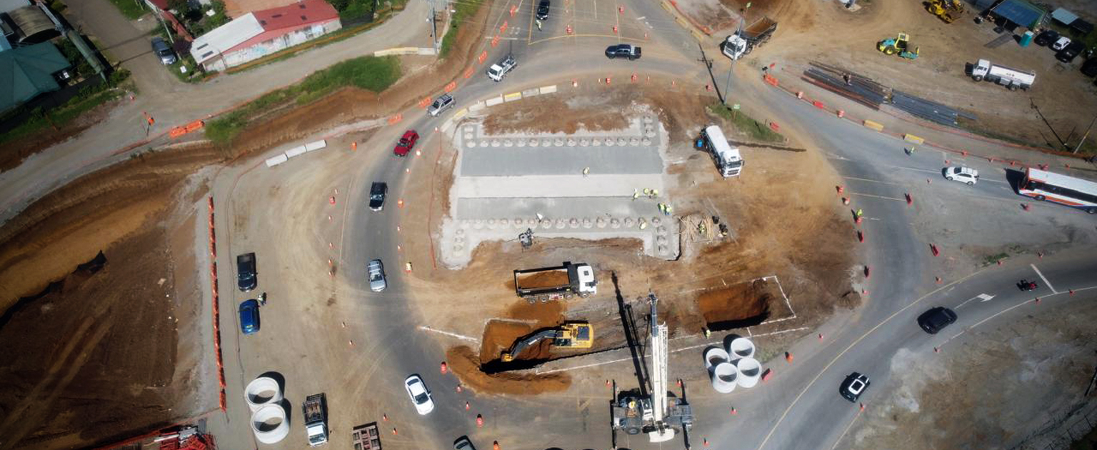 Vista aérea de las obras de construcción del paso subterráneo en la entrada al cantón de San Ramón. Se observan excavaciones, maquinaria pesada, elementos prefabricados de concreto y desvíos temporales que permiten mantener la circulación vehicular durante los trabajos