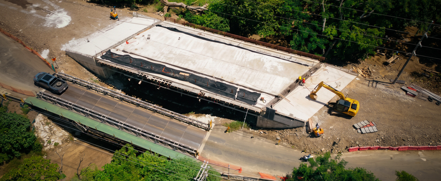 Fotografía aérea que muestra los trabajos en el puente sobre el río Soncoyo, se aprecia la estructura nueva contiguo al paso provisional