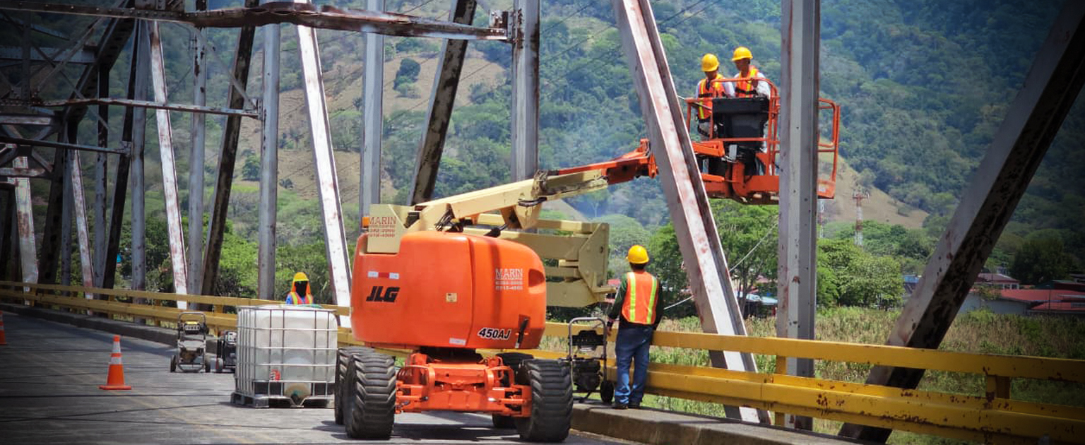 Fotografía que muestra maquinaria y personal trabajando en la parte superior del puente